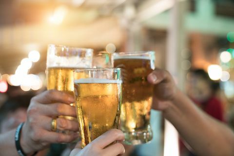 Vänner som skålar med glas lättöl på puben. Vacker bakgrund av Oktoberfest. En grupp unga människor medan de kopplar av i baren. fint korn. Mjukt fokus. Grunt DOF.