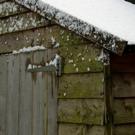 snö på taket av gamla timmer trädgårdsskjul