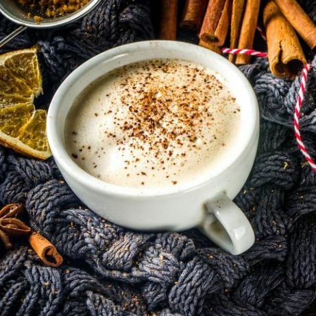 höst söt varm dryck, chai smörad rom, pumpa paj eller pumpa krydda kaffe latte mysig höst bakgrund med traditionell latte kopp, kryddor och gammal tröja, på rustik trä bakgrund