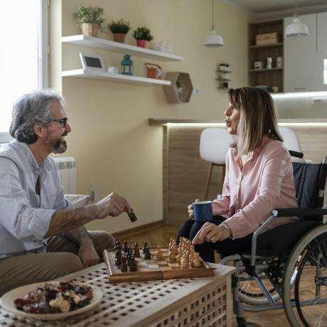 man och kvinna i rullstol spelar schack