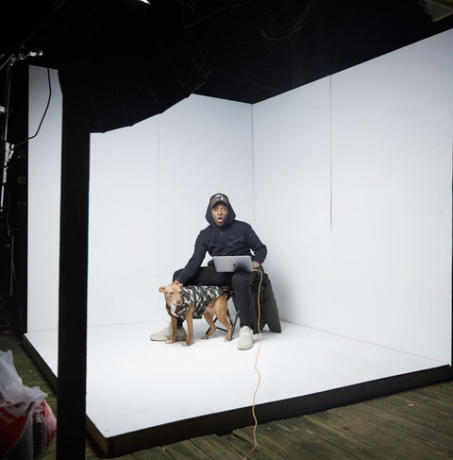 en man sitter inne i en vit fotostudio med en hund bredvid sig