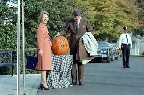 på det här fotografiet beundrar president Ronald Reagan en pumpa snidad med sloganen " håll kursen" använde president Reagan sloganen under 1982 mellanårsval första damen nancy reagan poserar bredvid pumpan de två står utanför södra portikens ingång till den vita hus