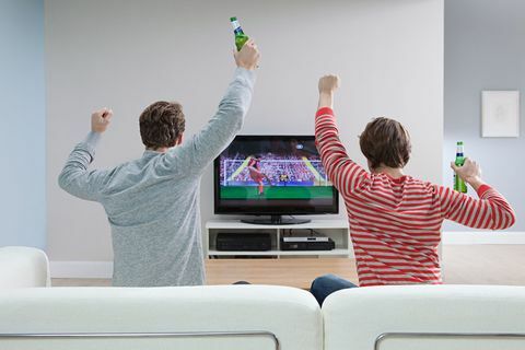Två män som tittar på fotboll på tv