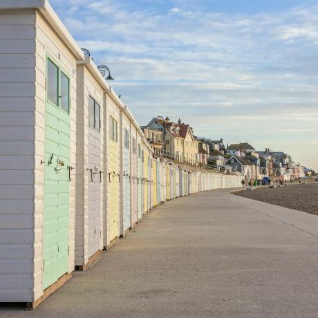 Pastellfärgade strandhyddor kantar strandpromenaden i Lyme Regis, Dorset