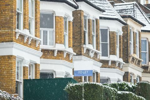 att låta skylt visas utanför radhus under snöfall runt crouch end-området i norra london