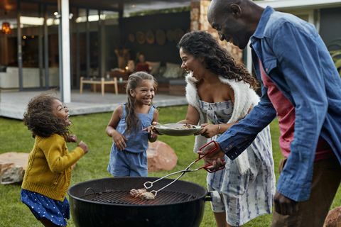 Familjmatlagning på grillen i deras trädgård