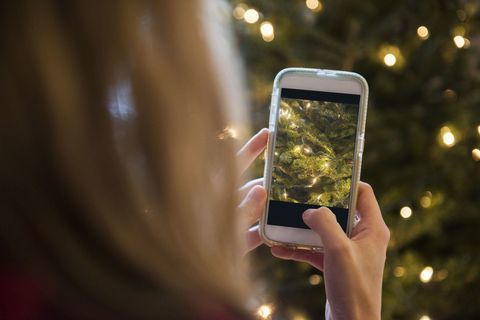 Kvinna som fotograferar julgranen med mobiltelefonen