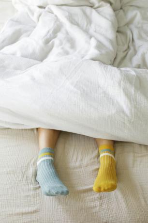 kvinna som bär blå och gula strumpor i sängen