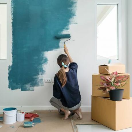 kvinna som målar en vägg blå