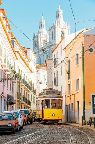 gul spårvagn på den smala gatan i Alfama-distriktet i Lissabon, Portugal