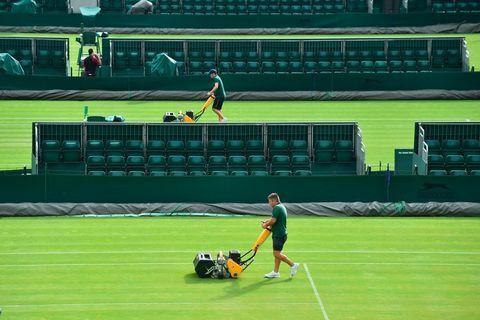 Markpersonalen klipper gräset på en domstol i The All England Lawn Tennis Club i Wimbledon