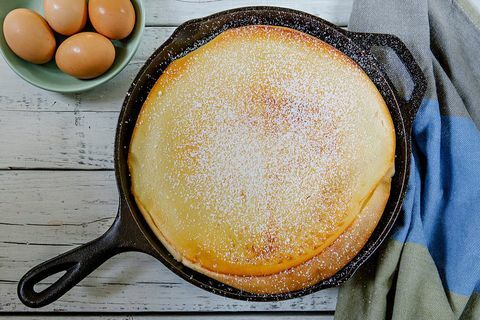 Pannkaka i stekpanna nära bunke med ägg på tabellen