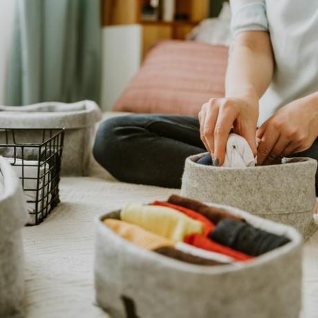 kvinna som organiserar kläder i garderob, lägger skjortor i lådor begrepp för ordning, minimalistisk garderob, japansk t -shirt fällningssystem och klädförvaring